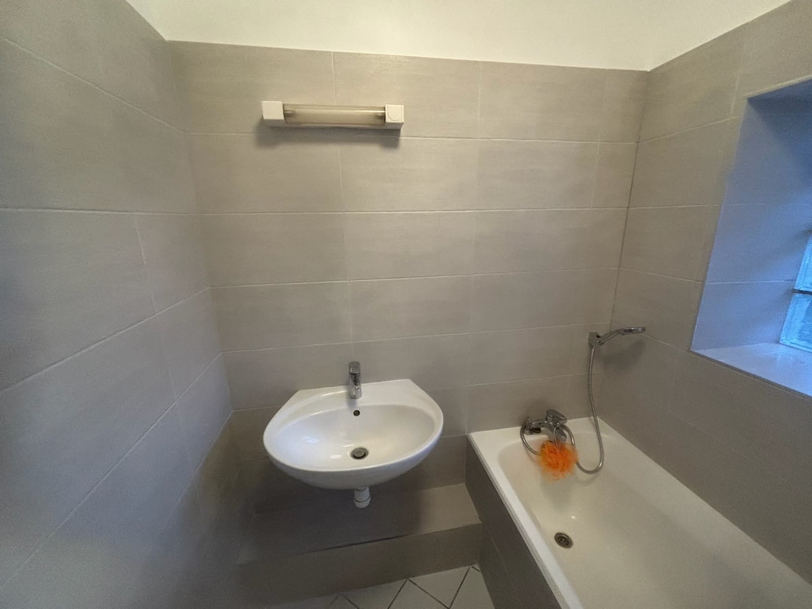 Lavabo, baignoire et carrelage gris terminés dans la même salle de bain